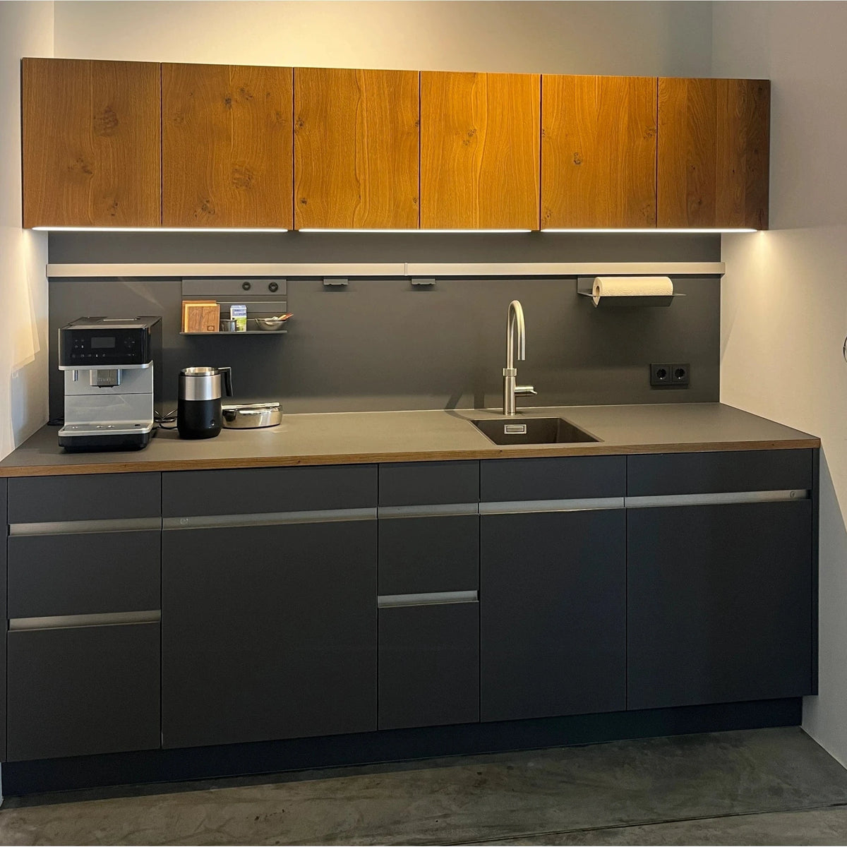 Schwarze kleine Büro Teeküche mit einer Eichenholz-Front in der Ausstellung der Küchen Schreinerei bei Stuttgart und Ludwigsburg.