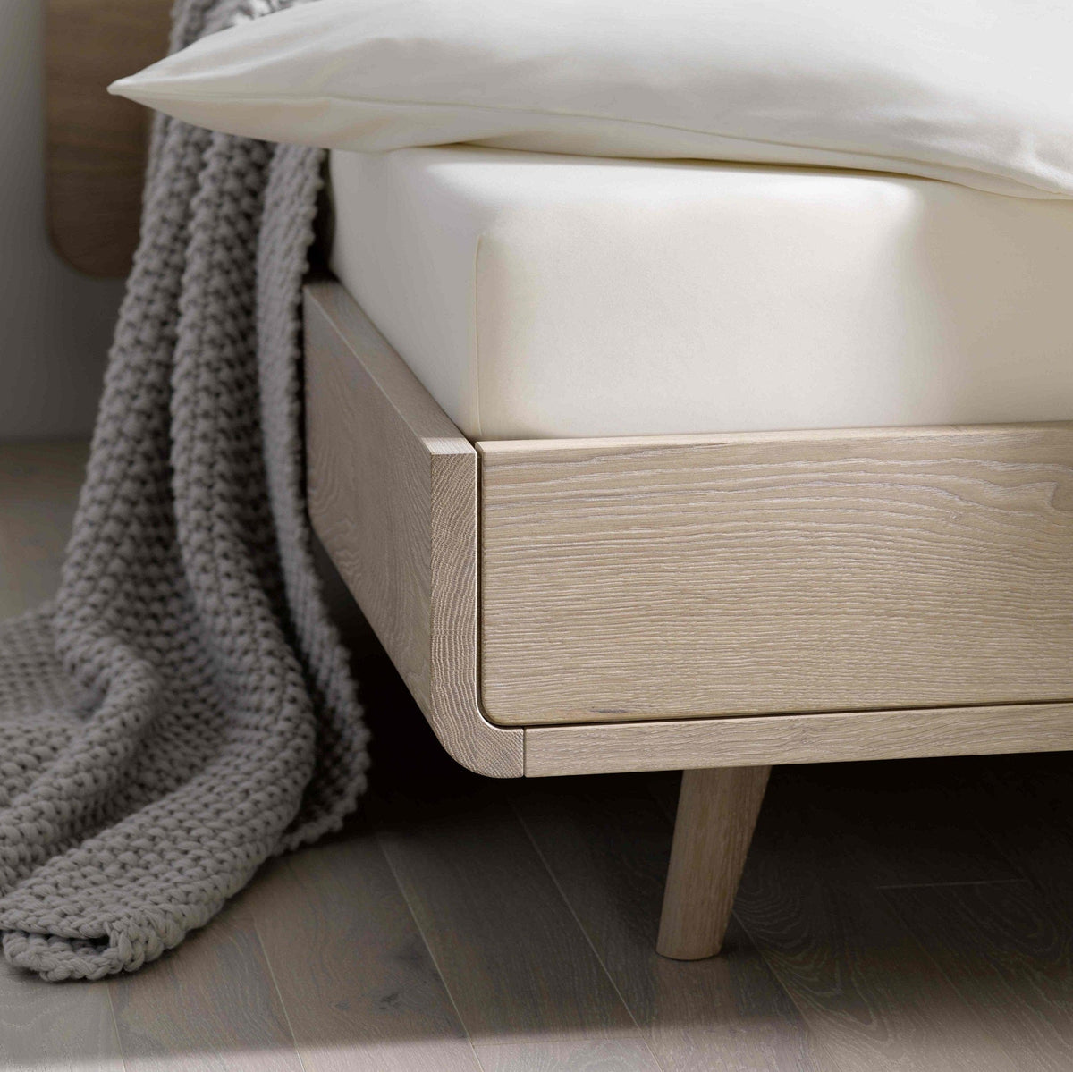 Detail vom Design Bett TALOS der Holzmanufaktur: Bett aus Eiche mit hohem Holzkopfteil im Boxspring Look.