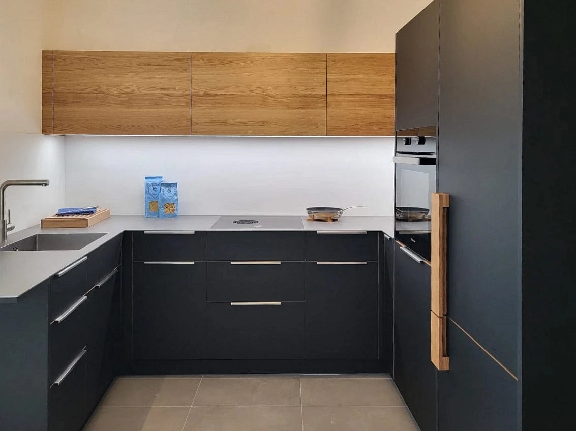 Eine ausgefallene kleine Küche in U-Form. Schwarzes Fenix kombiniert mit massivem Wildeiche-Holz und grauer  Keramik-Arbeitsplatte von Dekton.